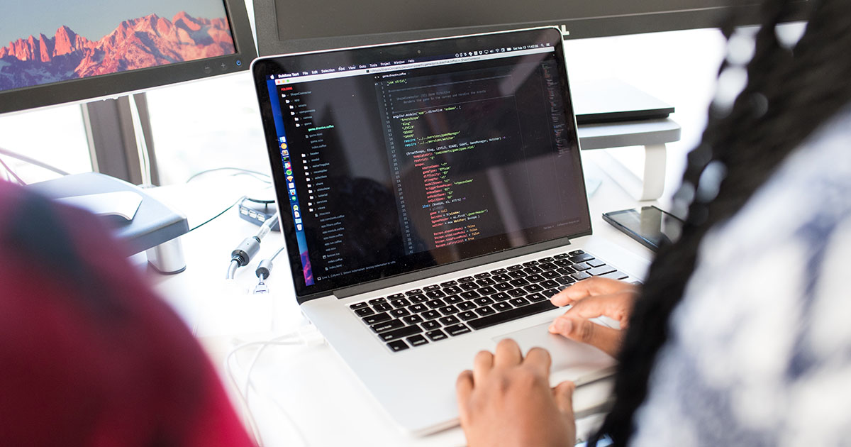 Over business person's shoulder looking at laptop screen with code