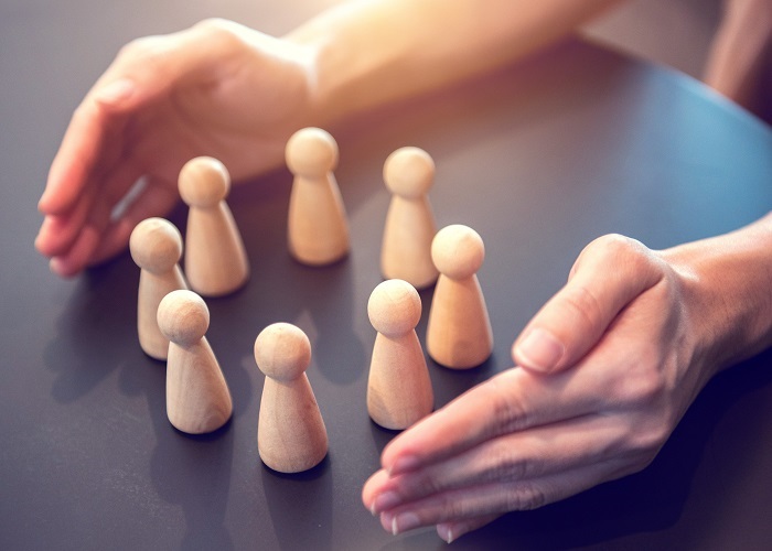 hands embracing a circle of small wooden figures