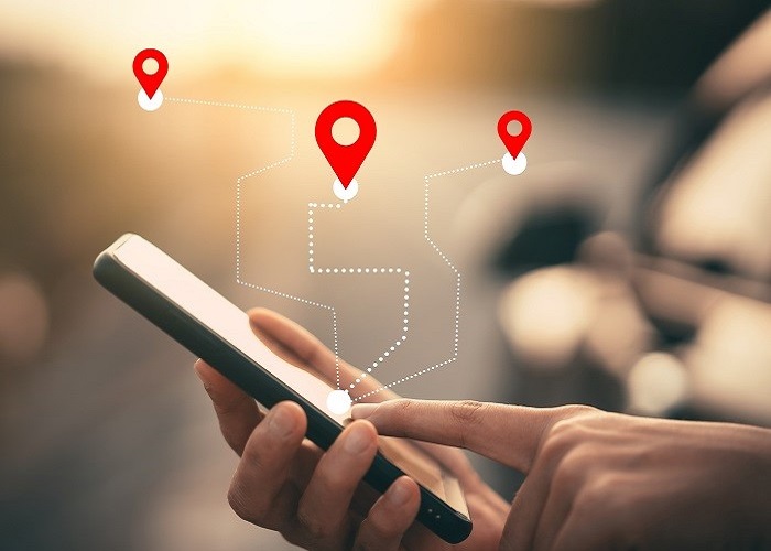 woman tapping a phone with graphic overlaid of lines stretching out to destination markers