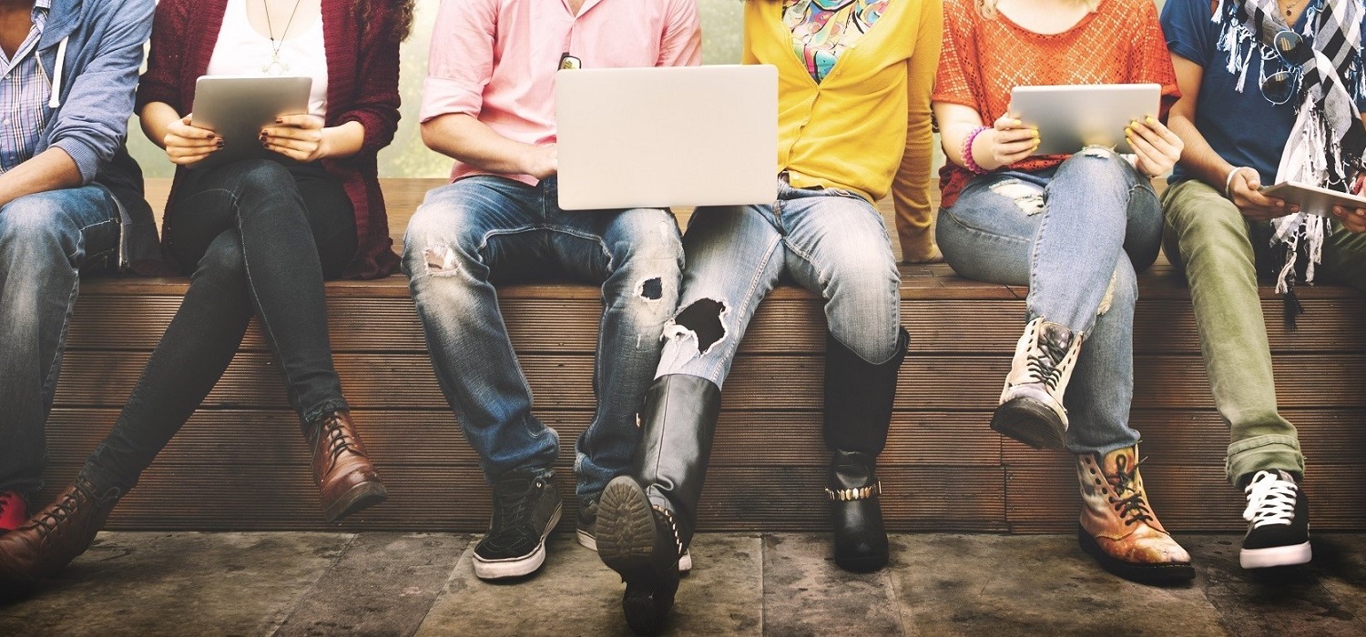 college students sitting on bench with laptop