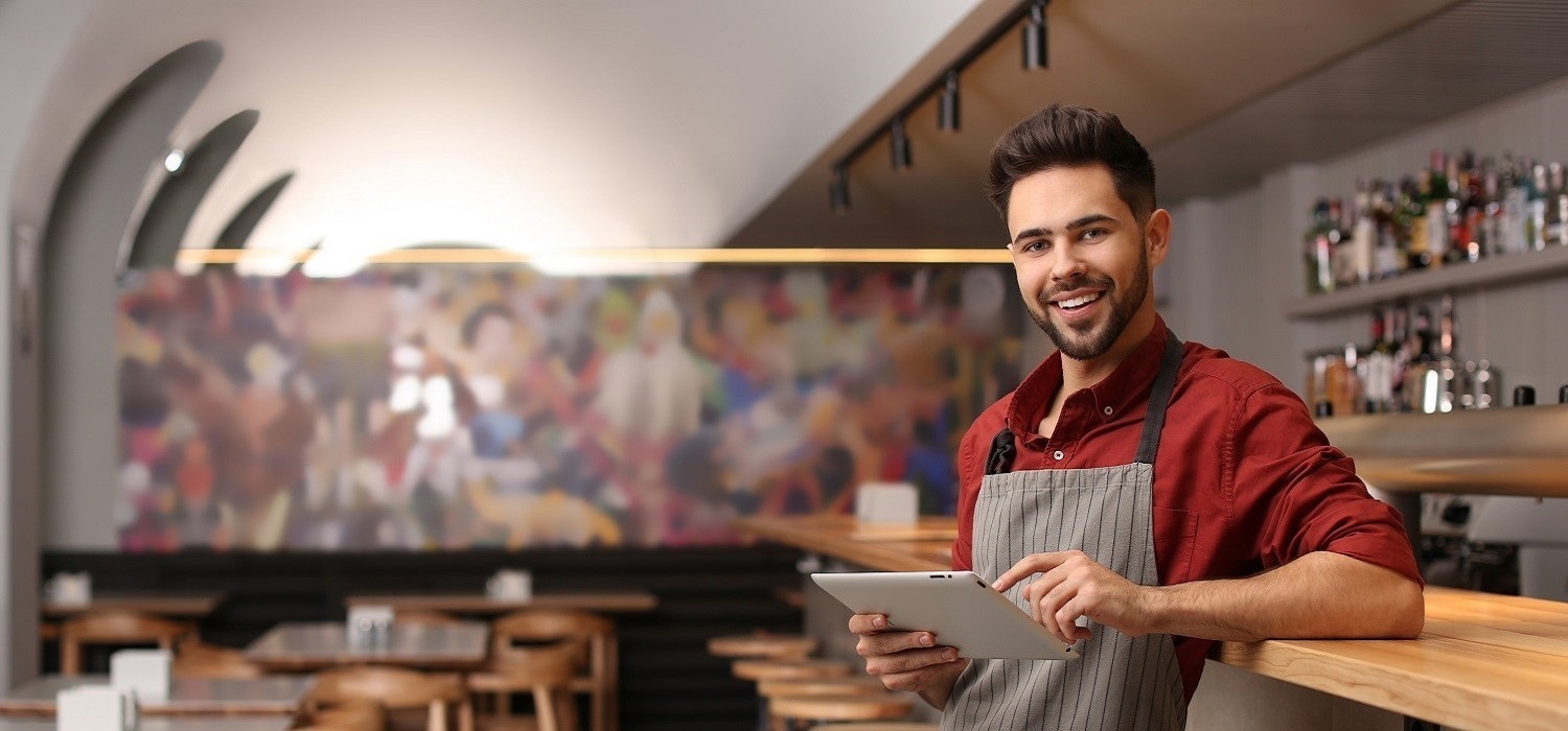 cook with pad standing in restaurant smiling