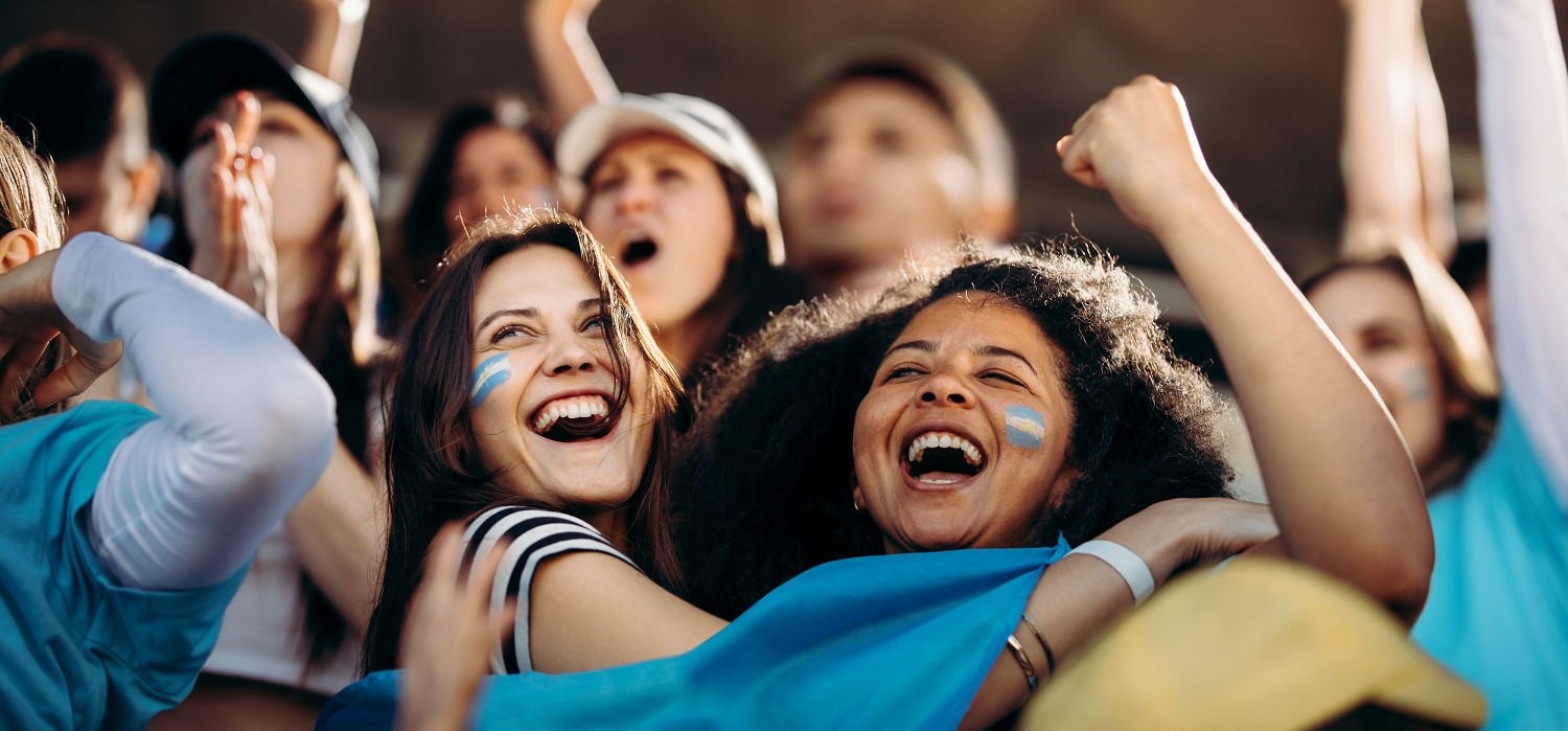 two women embrace each other at a crowd during a sports game