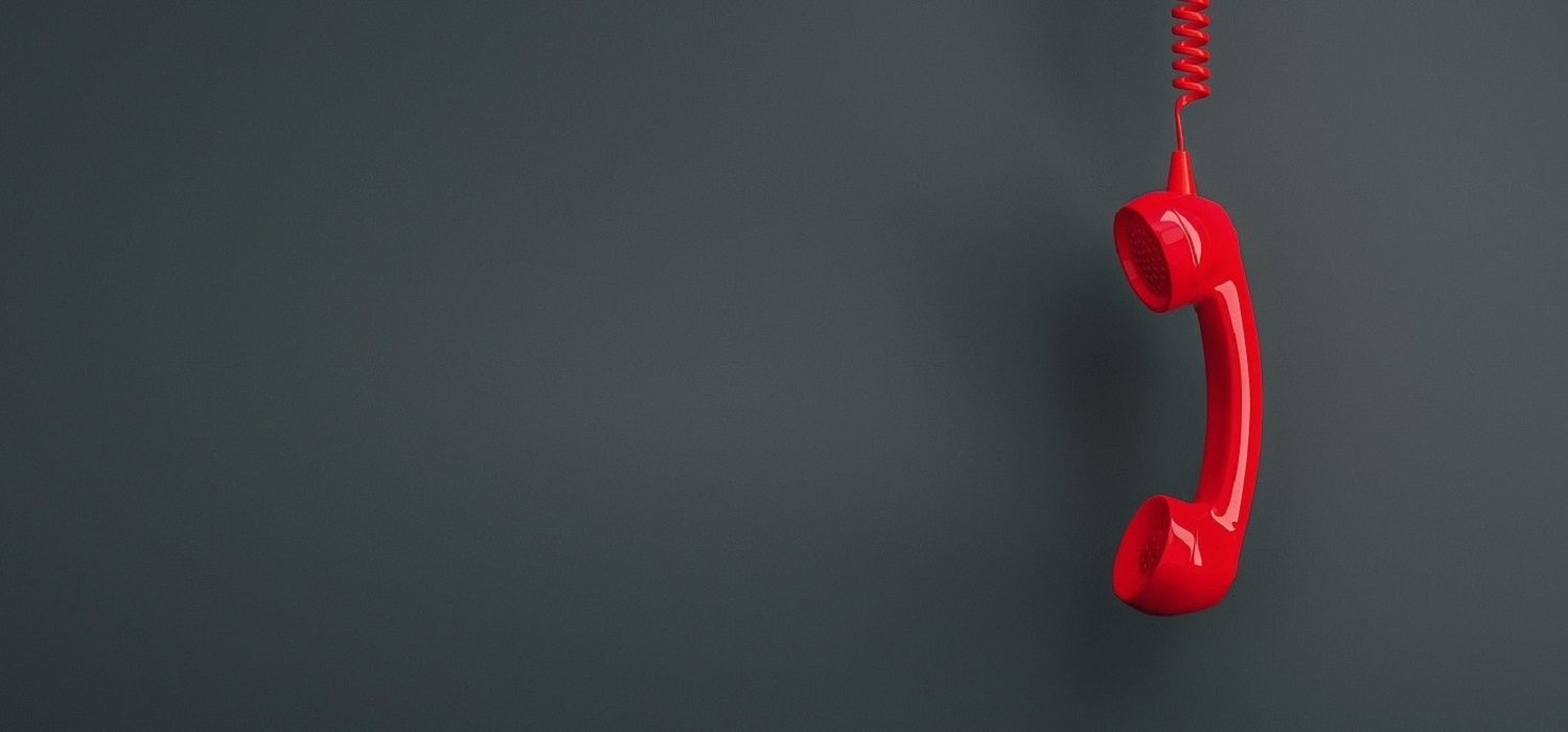 bright red phone on cord hanging upside down on dark background