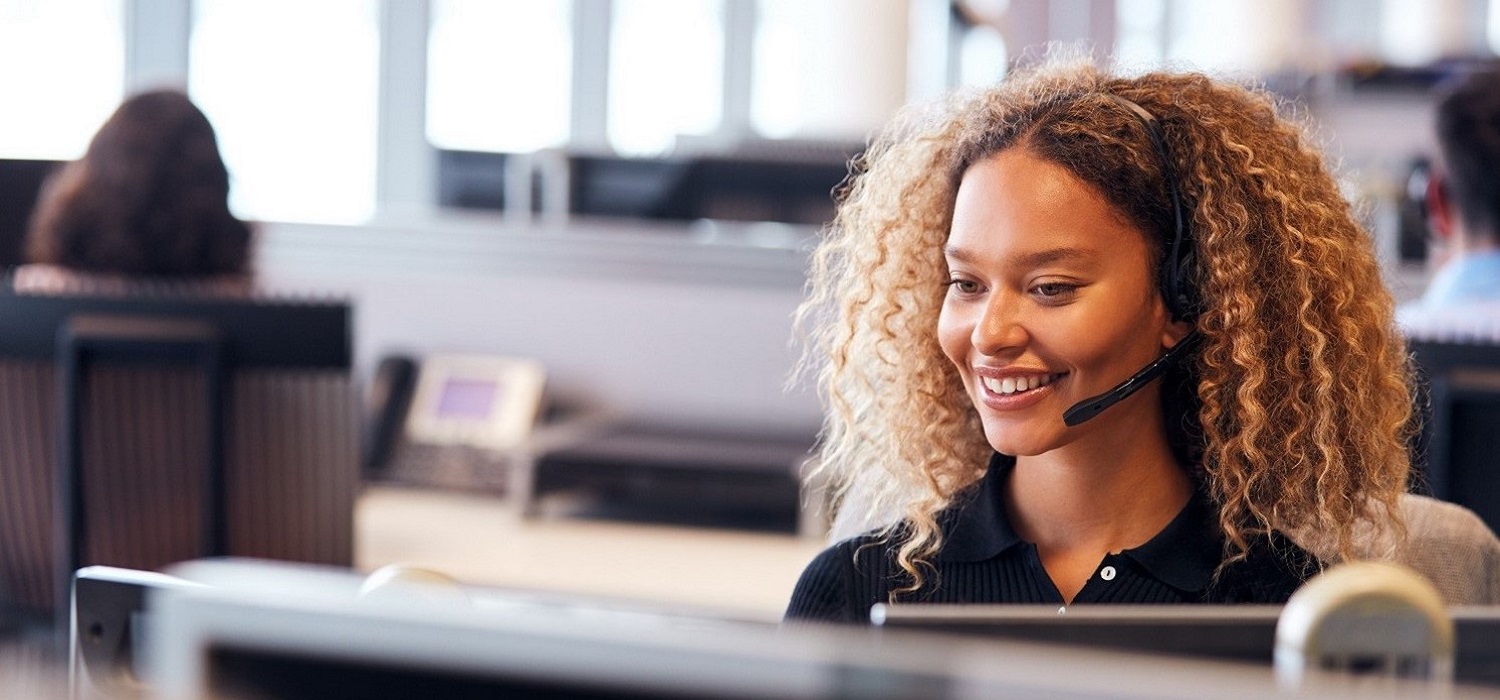 young woman with headset sitting at desk in call center