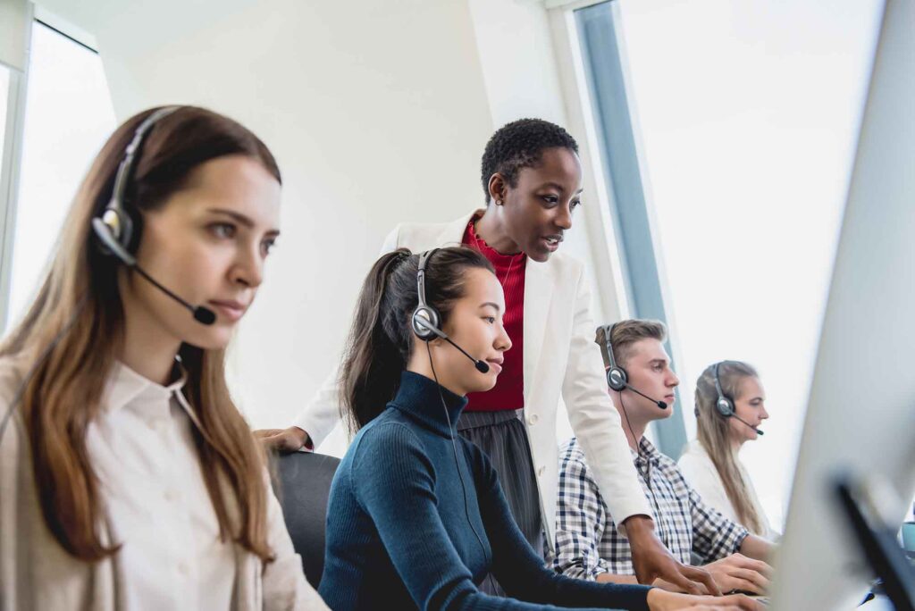a group of call center agents lined down a desk with headsets on